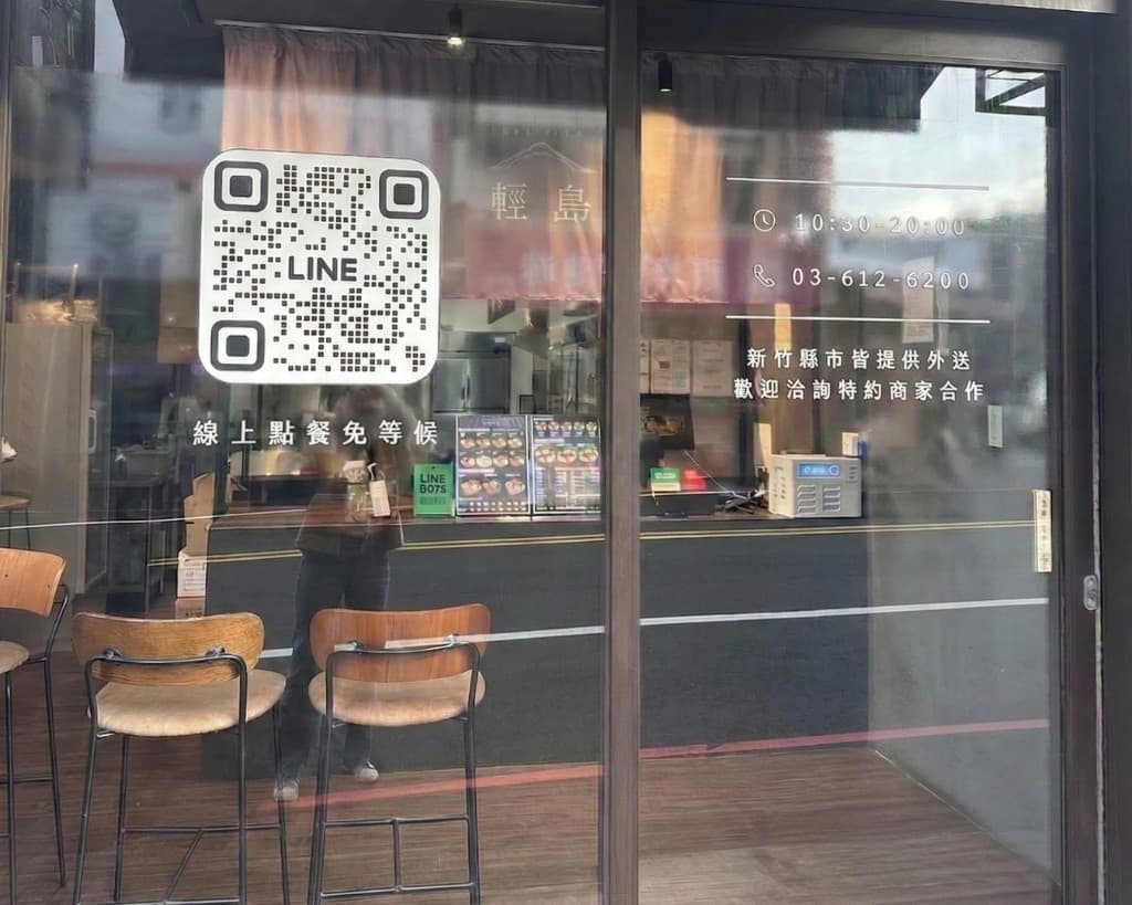輕島門市玻璃門面：線上點餐免等候 QR、營業時間、電話與外送說明，店內高脚椅與櫃檯
